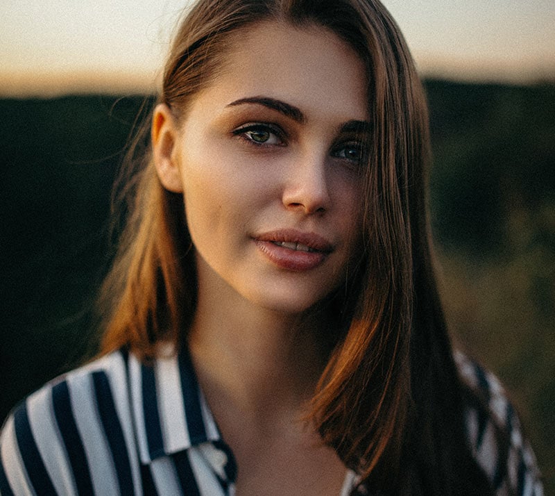 Donna sorridente in un campo al tramonto.