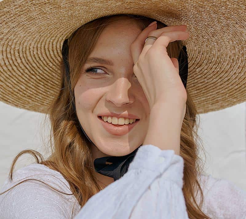 Donna con cappello di paglia che sorride al sole.