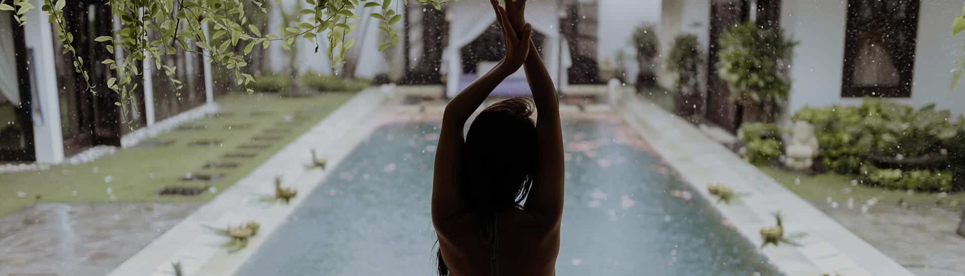 Donna che si rilassa in una piscina all'aperto con giardino curato.
