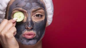 Maschera viso detox con argilla e cetriolo, applicata da una donna con cuffia.
