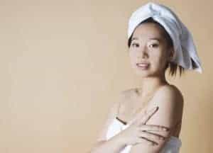 Viso di donna con asciugamano sulla testa e pelle luminosa, pronta per la cura del viso o un trattam.