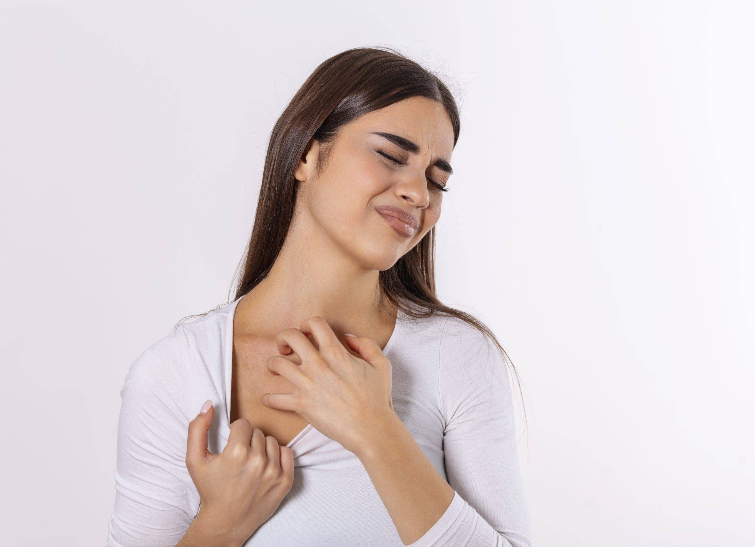 Young woman scratching her neck due to itching on a gray background. Female has an itching neck. The concept of allergy symptoms and healthcare