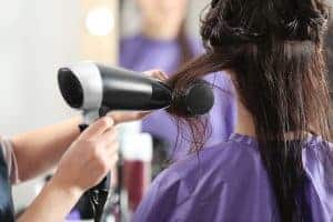 Asciugacapelli in uso durante un trattamento di bellezza, con una cliente con capelli umidi.