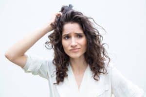 Donna confusa che si gratta la testa, esprime dubbio o incertezza.