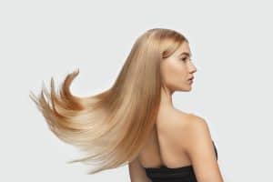 Capelli lisci e lucenti, donna con acconciatura elegante e capelli dorati.