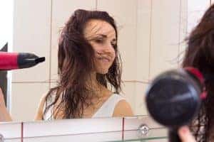 Donna che si prende cura dei capelli davanti allo specchio.