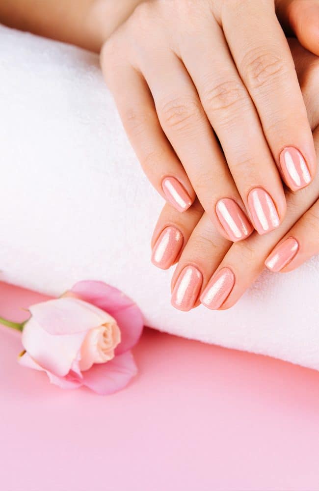 Unghie curate e lucide con smalto rosa chiaro.