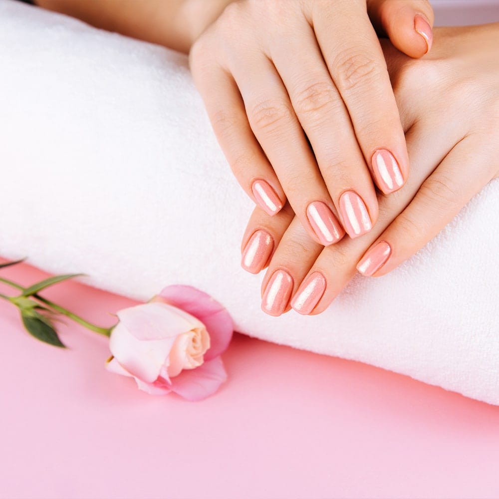 Unghie curate e lucide con smalto rosa chiaro.