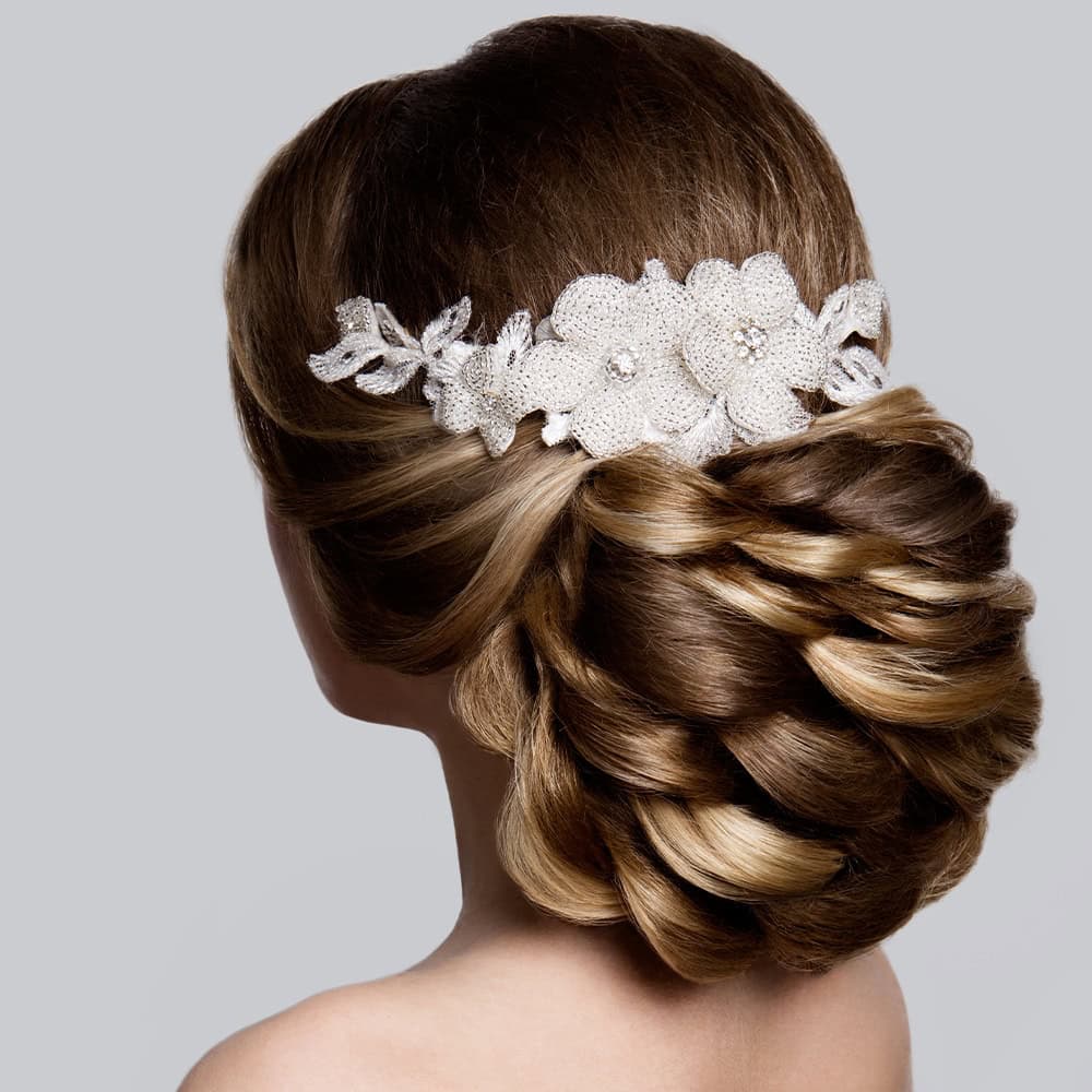 Acconciatura sofisticata con fiore bianco e intrecci, perfetta per occasioni speciali.