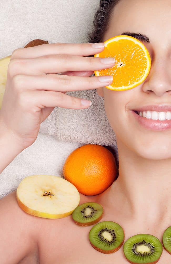 Frau con frutta fresca e arancia, promuovendo salute e bellezza naturale.