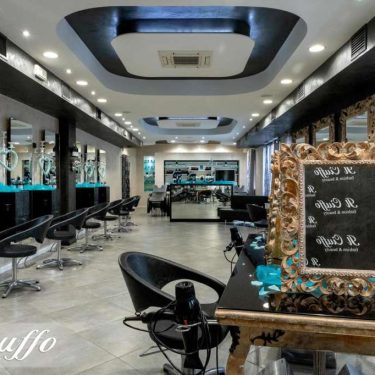 Salone di bellezza moderno con specchi e sedie nere, ambiente luminoso e accogliente.