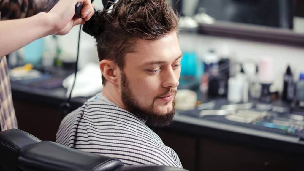 Uomo con capelli corti in salone, parrucchiere al lavoro.