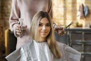 Donna in salone di bellezza riceve trattamento capelli, ambiente moderno.