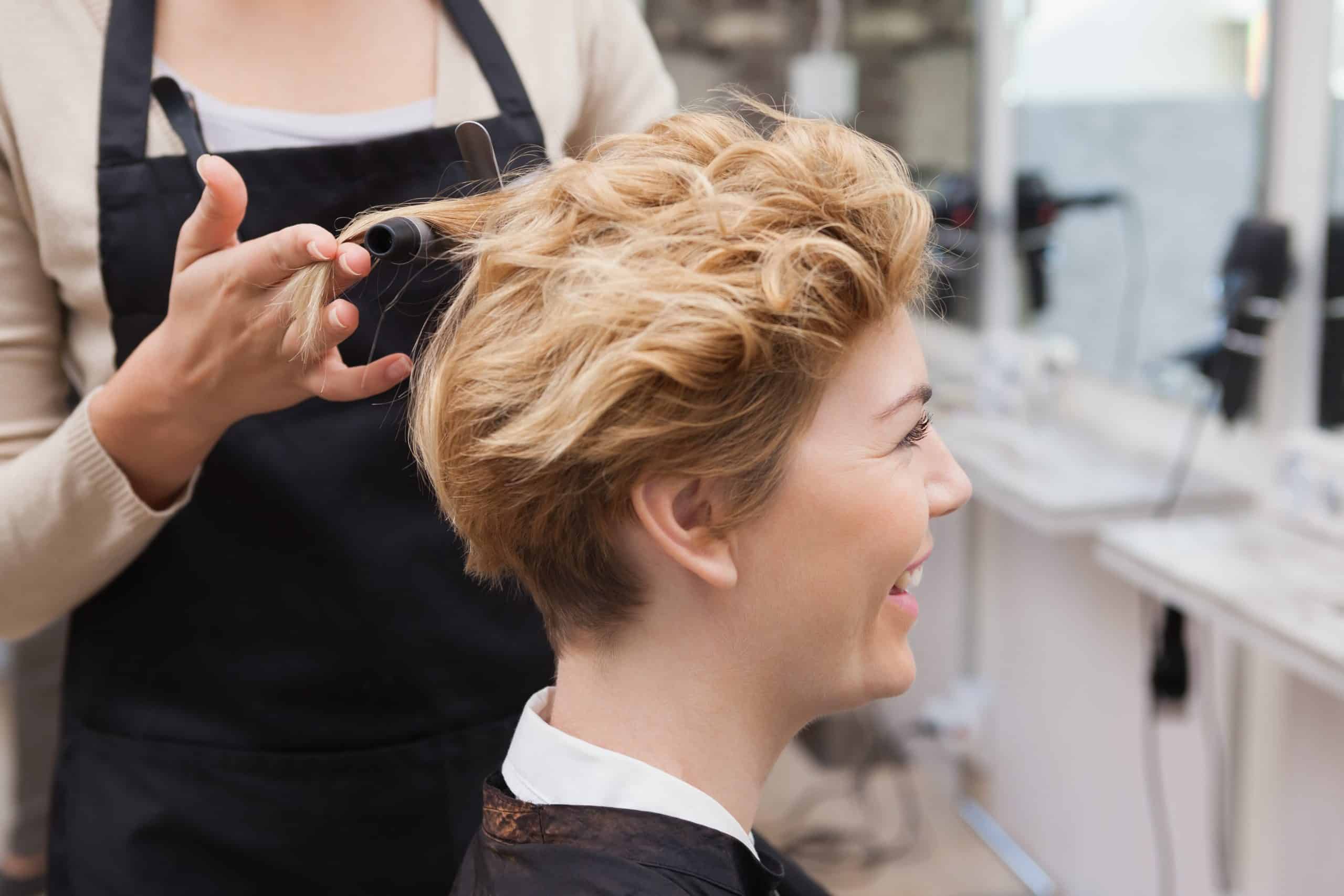Acconciatura di una donna con capelli corti e ricci, realizzata da un parrucchiere in un salone di b.